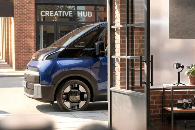 Kia PV7 i blå lak set skråt forfra i et bymiljø. Teaserbillede fra Kia.