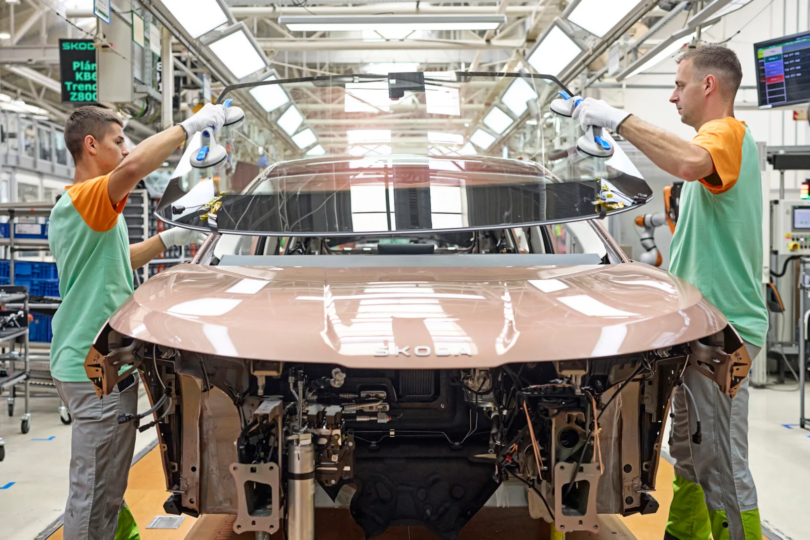 To medarbejdere monterer forruden på en Skoda Peaq på produktionslinjen i Mladá Boleslav